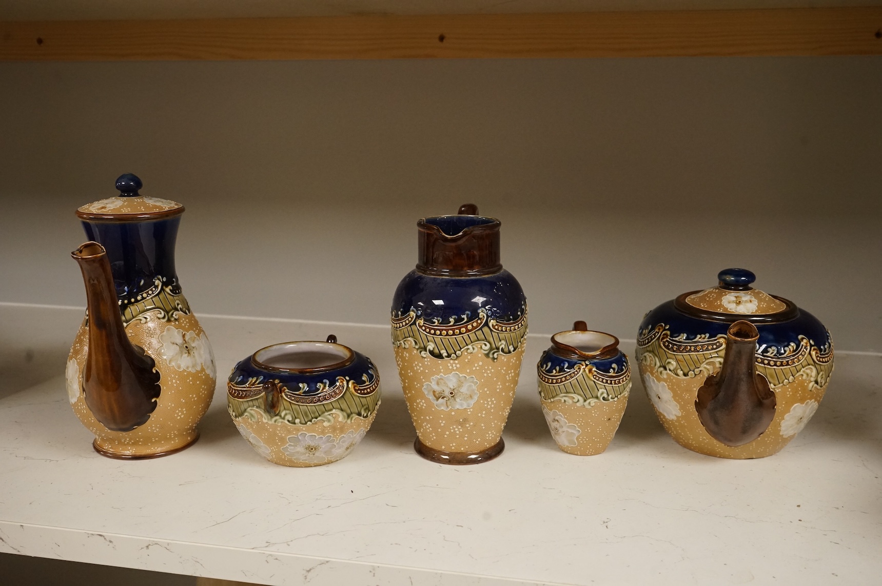 A small collection of Doulton Lambeth stoneware comprising, tea and coffee pots, two jugs and sugar bowl, largest 21cm high